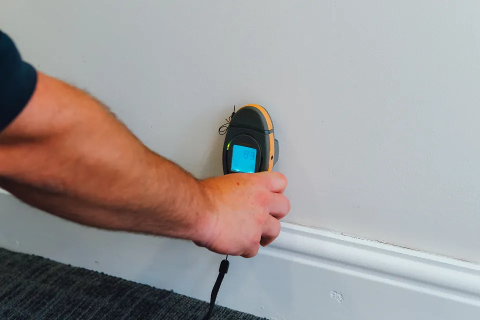 Moisture meter reading on an internal wall to trace damp from a leak above